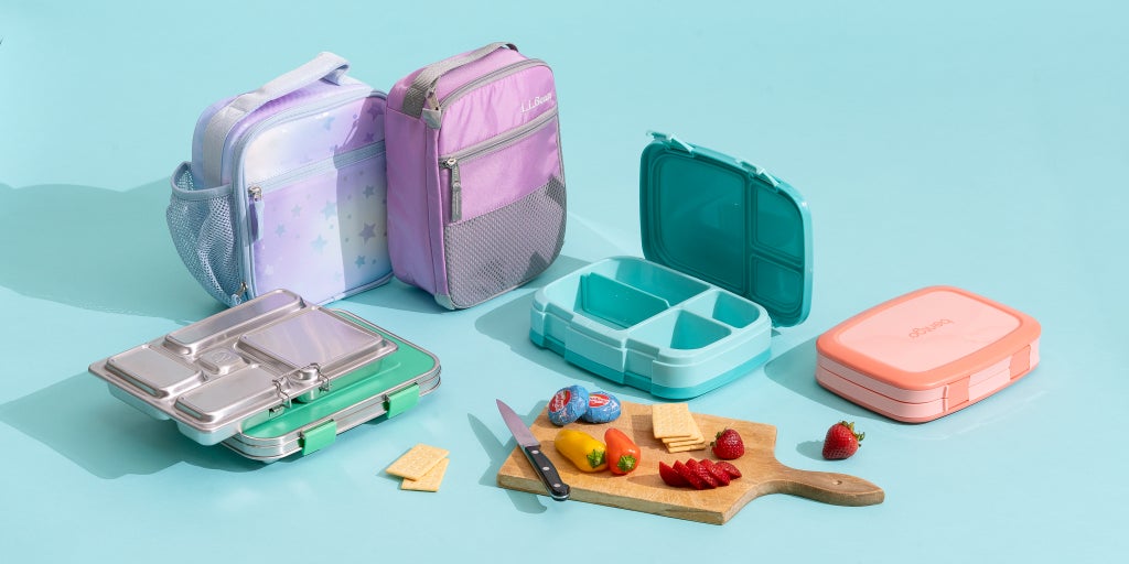 A selection of the lunch boxes we tested to find the best, with a cutting board and snacks.